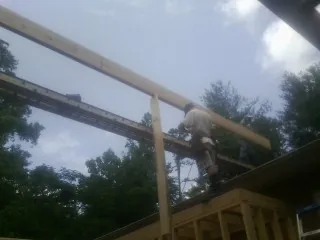 Carpenter setting a ridge beam over a new addition frame — Ice Dam Removal by Roofing Brothers in Partlow