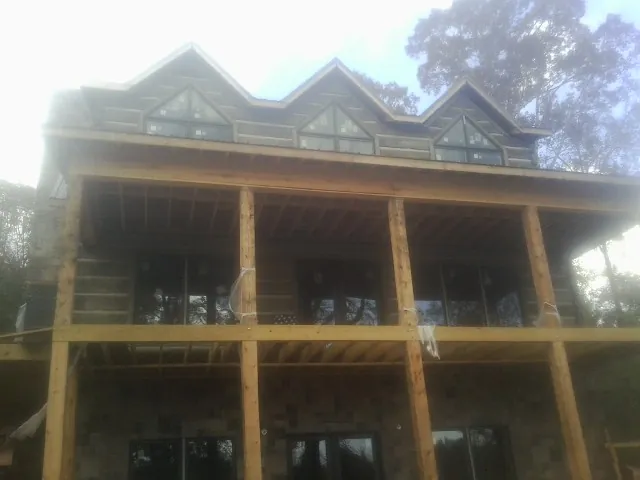Dormers and porch framing on a large log home under construction — Roof Coating work by our crew in Partlow