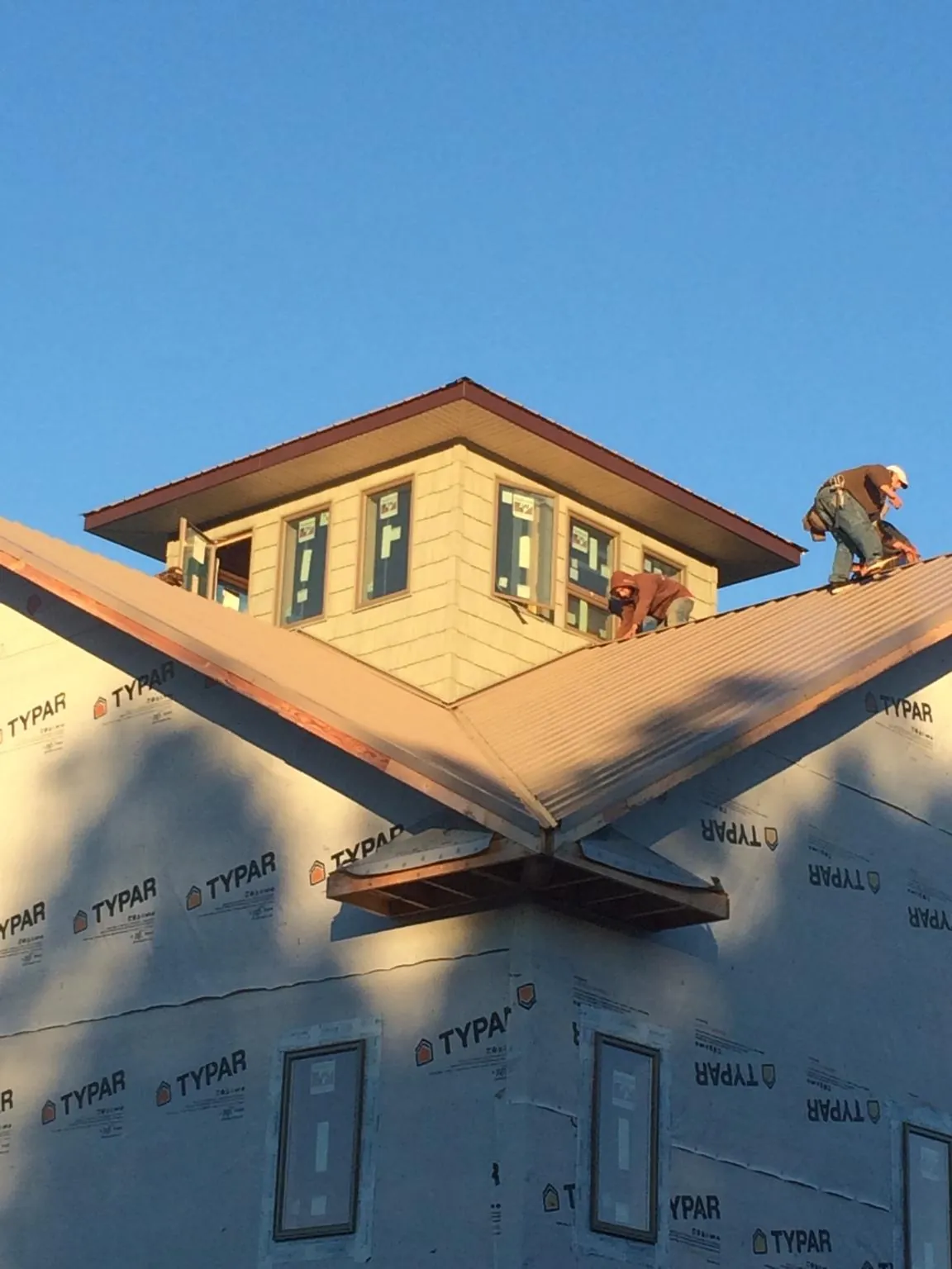 Roofers working around a rooftop cupola on a new metal roof at sunset — Roof Waterproofing in Partlow by Roofing Brothers